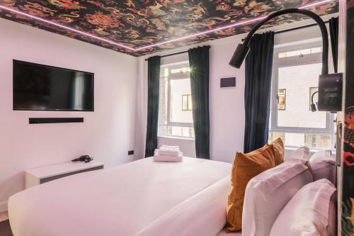 een kamer met een bed en een televisie aan het plafond bij WelcomeStay Fitzrovia Two Bed Apartments - Sleep in Opulent Luxury in Londen