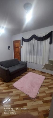 sala de estar con sofá y alfombra rosa en Apartamento praia B, en Mongaguá