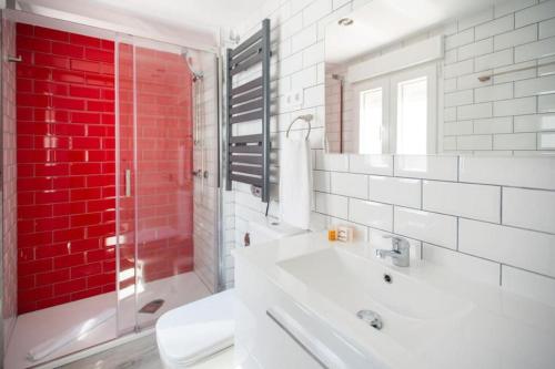 Baño blanco con pared roja en Fantastic flat in Call-Preciados-Gran Vía 4P, en Madrid