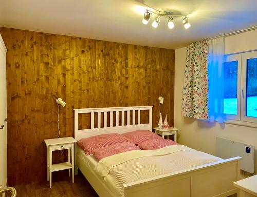 a bedroom with a bed and a wooden wall at Chalupa 96 in Víchová nad Jizerou