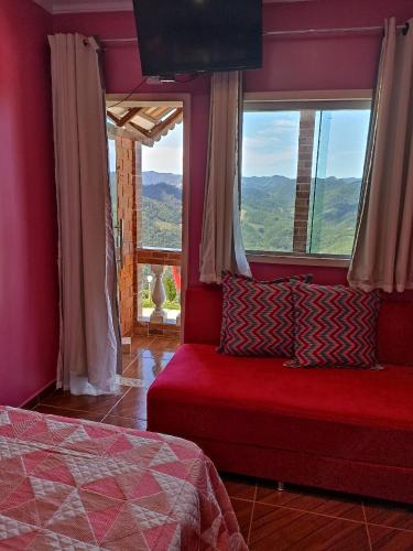 een slaapkamer met een rood bed en een raam bij Pousada Linda Vista in Domingos Martins