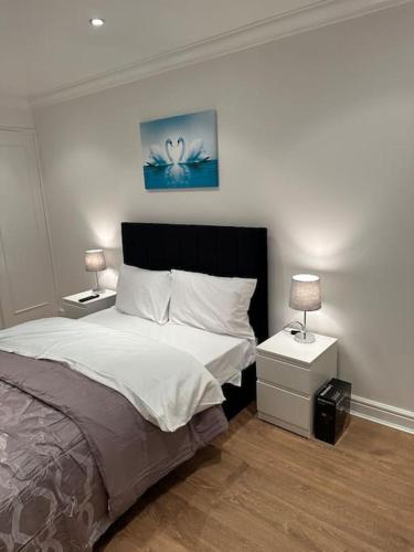 1 dormitorio con 1 cama y 2 mesitas de noche con lámparas en Beautiful 3 Bedrooms town house with parking, en Redbridge