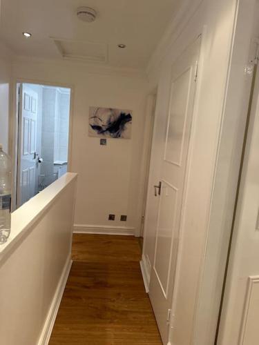 a hallway with a white door and a wooden floor at Beautiful 3 Bedrooms town house with parking in Redbridge