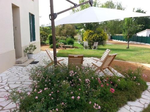 - une terrasse avec 2 chaises, un parasol et des fleurs dans l'établissement Maison de famille Benaiteau à 10' du Puy du Fou, à Puy-du-Fou