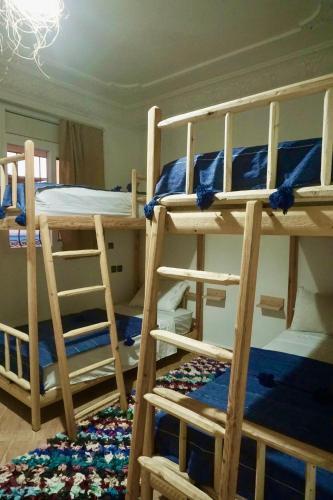 a room with three bunk beds and a rug at Caban Surf in Tamraght Ouzdar