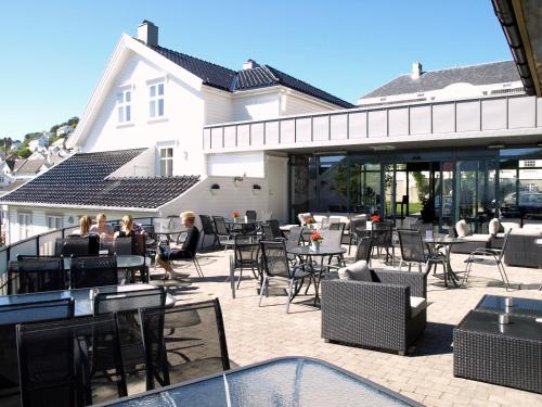a group of people sitting at tables and chairs on a patio at Rederiet Hotel in Farsund