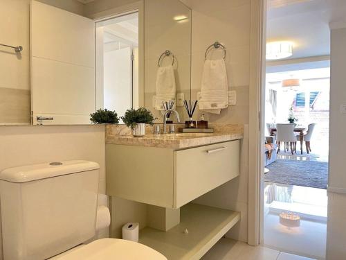 a bathroom with a toilet and a sink and a mirror at Apartamentos Dom Rolim no CENTRO by Achei Gramado in Gramado