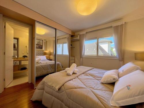 ein Schlafzimmer mit einem großen Bett und einem großen Fenster in der Unterkunft Apartamentos Dom Rolim no CENTRO by Achei Gramado in Gramado