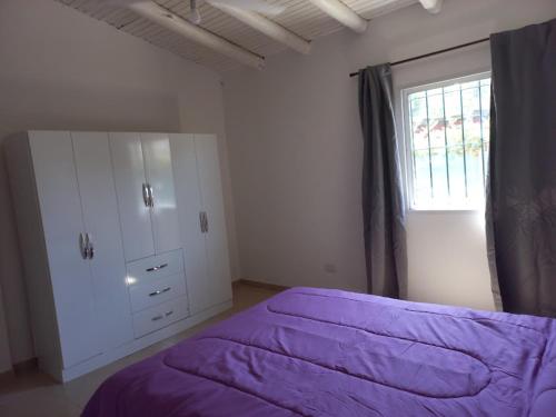 1 dormitorio con cama morada y ventana en Cabañas Vista Andes IV en Luján de Cuyo