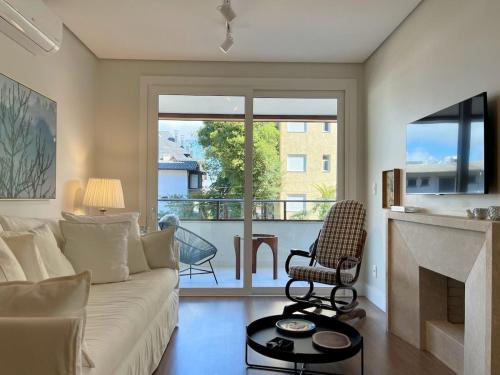 uma sala de estar com um sofá branco e uma lareira em Apartamentos L'adress Reserve CENTRO by Achei Gramado em Gramado