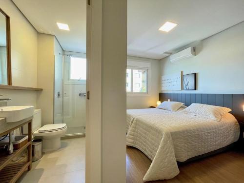 um quarto com uma cama e uma casa de banho com um lavatório em Apartamentos L'adress Reserve CENTRO by Achei Gramado em Gramado