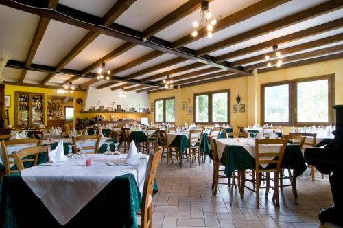 una sala da pranzo con tavoli, sedie e finestre di Hotel Gabriella a Fanano