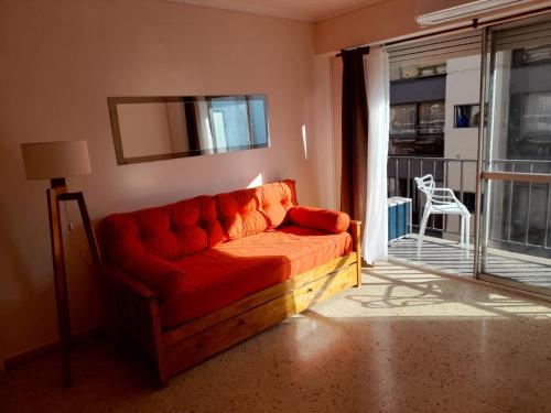 un sofá rojo en la sala de estar con balcón en Departamento reciclado a nuevo a 3 cuadras del mar en Mar del Plata