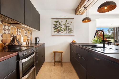 a kitchen with black cabinets and a sink at Byron Pacific Apartments - On Clarkes Beach in Byron Bay