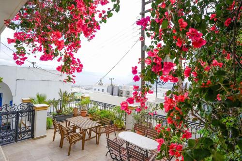 un patio con mesas, sillas y flores rosas en Fira Central Apartments with Veranda, en Fira
