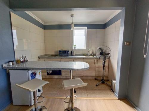 uma cozinha com uma mesa e dois bancos num quarto em Bello y cómodo departamento a minutos del centro em Santiago