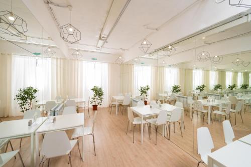 a dining room with white tables and white chairs at Hotel Prizma in Penza