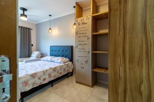 um pequeno quarto com uma cama e uma estante de livros em Apê Aconchegante Canto do Forte e Boqueirão em Praia Grande na Praia Grande