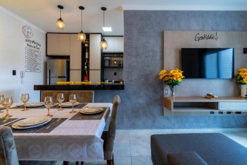 a dining room with a table with chairs and a tv at Apê Aconchegante Canto do Forte e Boqueirão em Praia Grande in Praia Grande