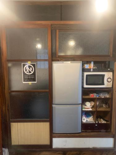 a small kitchen with a refrigerator and a microwave at 囲炉裏町家Guesthouse FUJITA 一棟貸切 villa 無料駐車場 in Hakusan
