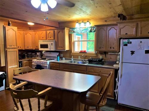 a kitchen with a table and a white refrigerator at Middle Pond Cabin- Direct ATV & Snowmobile Access in Pittsburg
