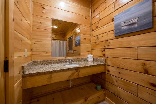 baño con lavabo en una cabaña de madera en Mountain Haven with 2 HotTubs, Thtr &Game Rm, Summer Special,1mi to the Parkway! - Ideal for Family Reunions or Group Getaways! Home away from home, en Pigeon Forge