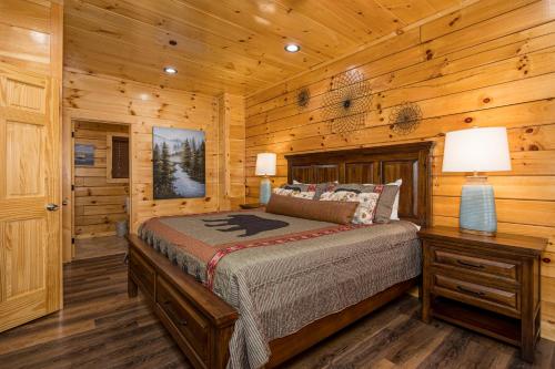 a bedroom with a bed in a log cabin at Mountain Haven with 2 HotTubs, Thtr &Game Rm, Summer Special,1mi to the Parkway! - Ideal for Family Reunions or Group Getaways! Home away from home in Pigeon Forge