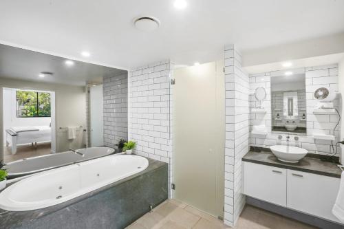 a white bathroom with a tub and a sink at 303 Sea Temple Renovated Apartment in Palm Cove