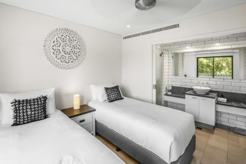 a white bedroom with two beds and a sink at 303 Sea Temple Renovated Apartment in Palm Cove