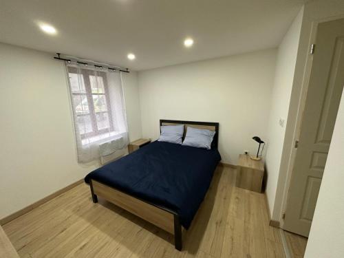 1 dormitorio con cama con sábanas azules y ventana en Le luron, en Lure