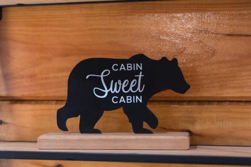 a black bear sign with the words raisin sweet cabin at 5Bd5B Escape Cabin with 2 HotTubs, Thtr &Game Rm,1mi to the Parkway! 4mi to Dollywood - Spring Deal in Pigeon Forge