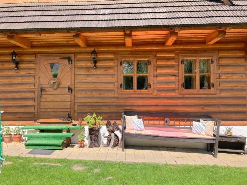 Cabaña de madera con 2 bancos y un gato sentado delante en Liptovská Drevenica en Liptovský Mikuláš