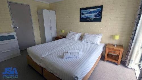 a bedroom with a large bed with white sheets and pillows at The Summit 10 in Jindabyne