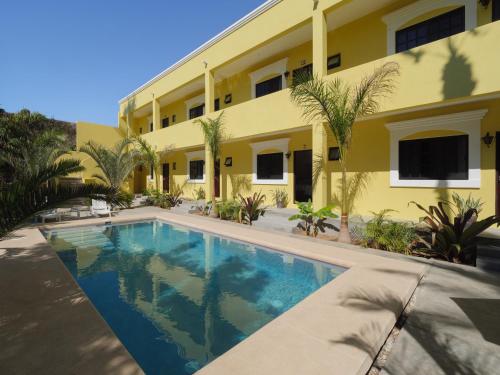 a swimming pool in front of a yellow building at Gallo Azul, Downtown Loft Style Apartment in Todos Santos