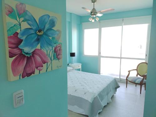 a bedroom with a bed and a painting of flowers at Departamento Nuevo 2 amb con cochera Solo parejas o familias in Mar del Plata