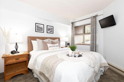 a white bedroom with a large bed and a window at Slopeside Whistler Creek in Whistler