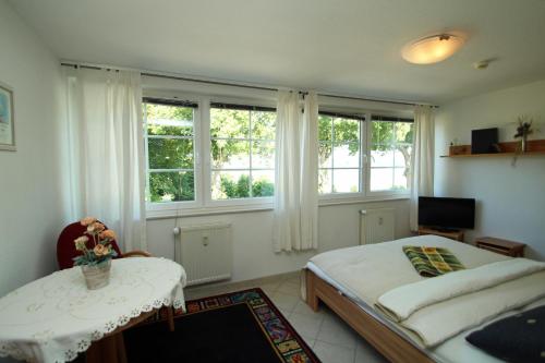 a bedroom with a bed and a table and windows at App Seeblick in ruhiger Lage in Seedorf in Seedorf