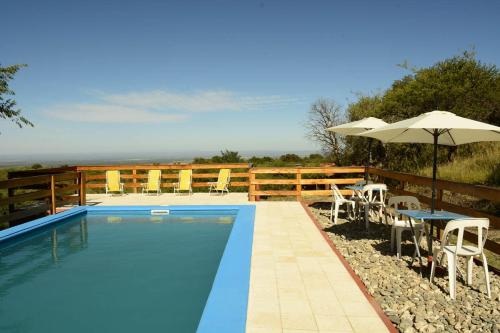 a swimming pool with chairs and an umbrella at Corazon de Montaña in Merlo