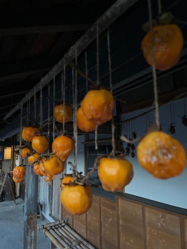 a bunch of oranges hanging on a wall at 体験型古民家宿 旅ノ舎 in Nissaka