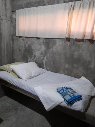uma cama com lençóis brancos e uma janela em DUMA HOSTEL em Dumaguete