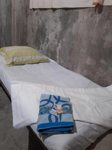 uma cama com lençóis brancos e toalhas azuis em DUMA HOSTEL em Dumaguete