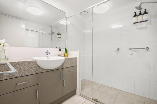 a white bathroom with a sink and a shower at Seapoint Unit 14 32 Victoria Tce Kings Beach in Caloundra