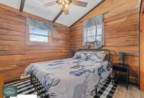 a bedroom with a bed with wooden walls and a ceiling at Cozy Cabin at Cloverdale Cabins in Hinckley