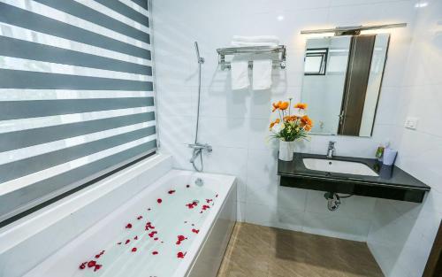a bathroom with a sink and a tub with flowers on the floor at Sea Breeze Villa FLC sang trọng gần biển có bể bơi in Sầm Sơn