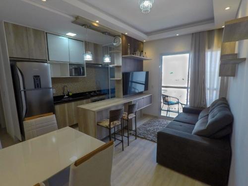 uma cozinha e sala de estar com um sofá e uma mesa em Apê aconchegante e seguro em Salto
