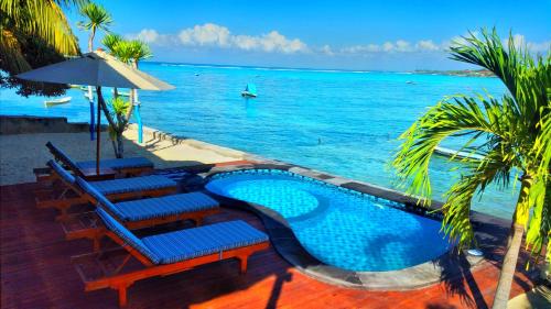 a swimming pool with lounge chairs and the ocean at Double'A beach house in Nusa Lembongan