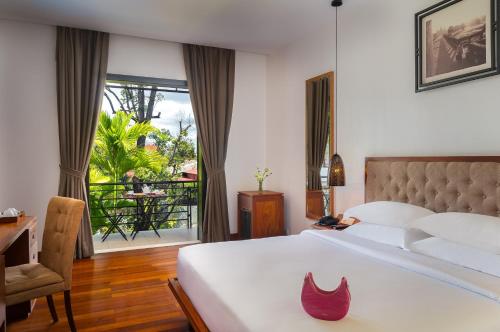 um quarto com uma cama, uma secretária e uma janela em Koulen Hotel em Siem Reap