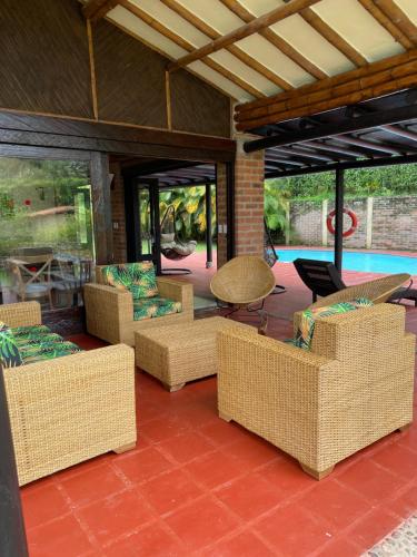 un patio con sillas de mimbre, mesa y piscina en Fincas Panaca Villa Portal 9, en Quimbaya