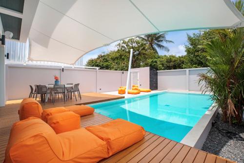 a living room with an orange couch next to a swimming pool at New & Elegant 5Br Pool Villa Samakki Garden 5 in Rawai Beach