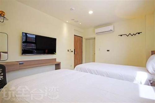 a hotel room with two beds and a flat screen tv at Smile Ocean Homestay in Green Island